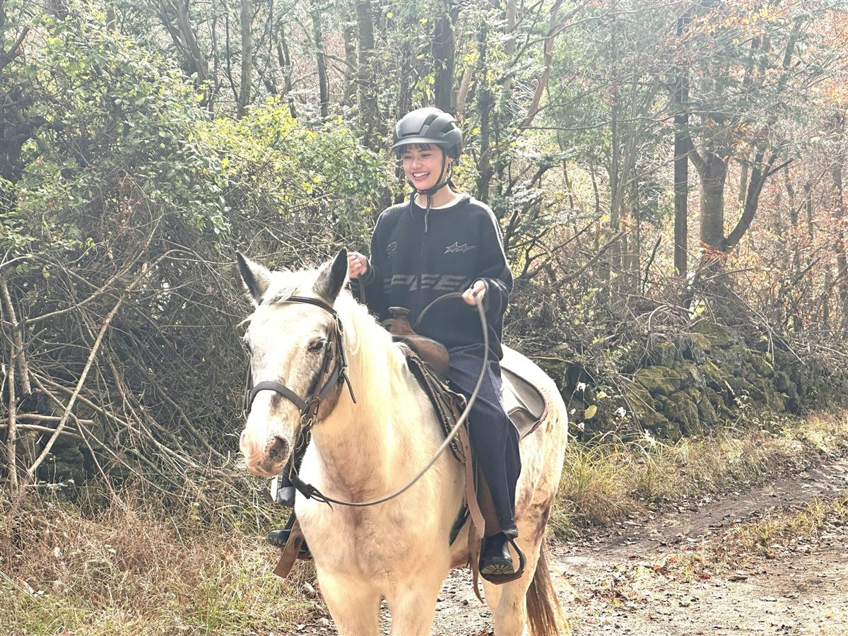 森の道を馬に乗って進む女性