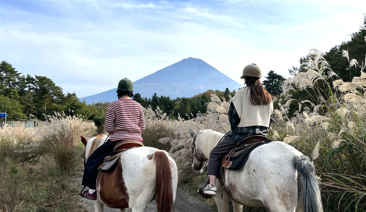 ススキの中を馬で進む二人と富士山